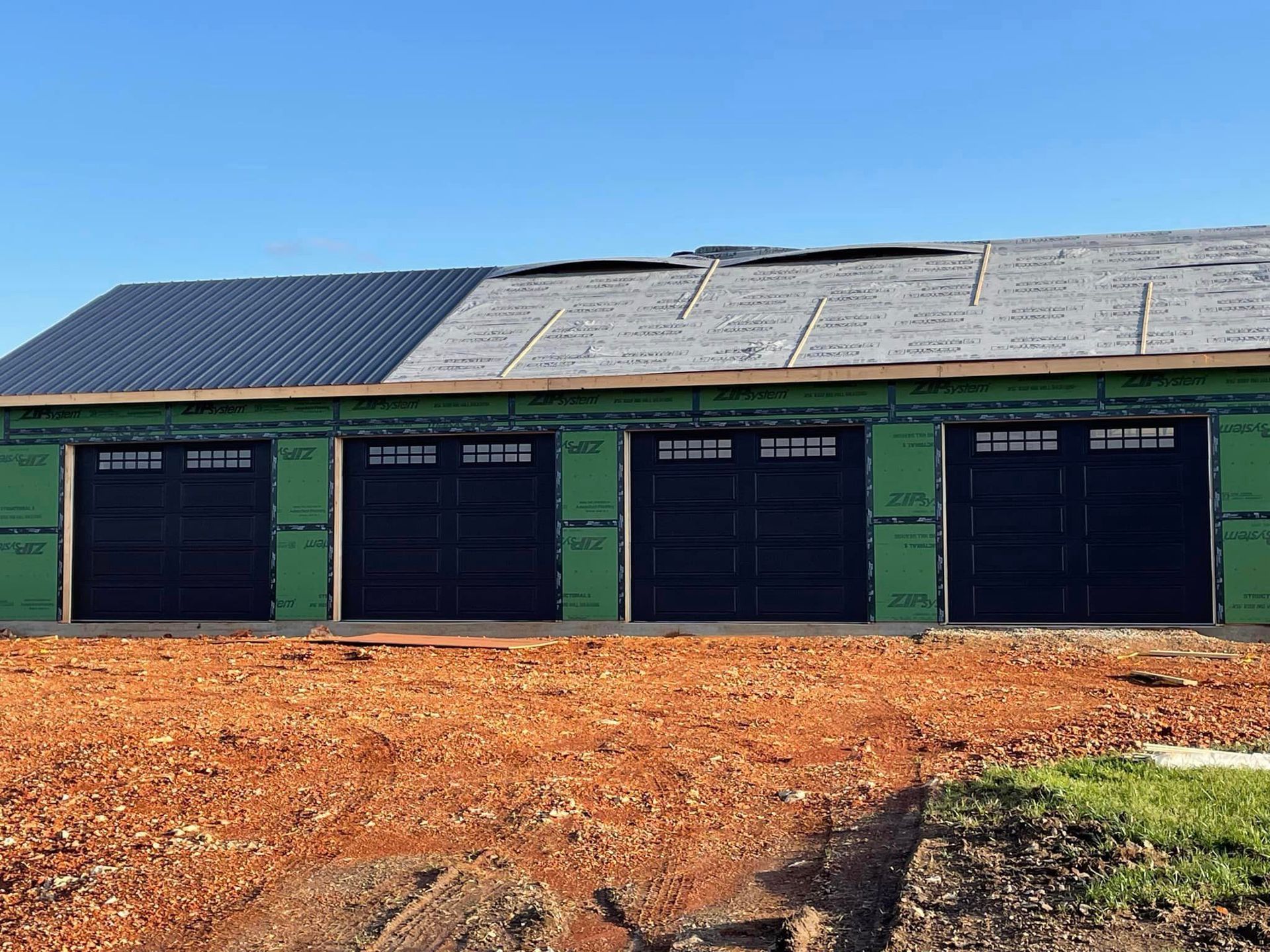 A building under construction with four garage doors and a roof.