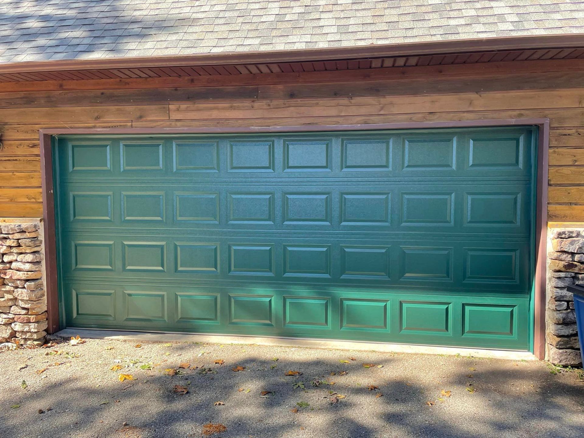 A green garage door is on the side of a house.