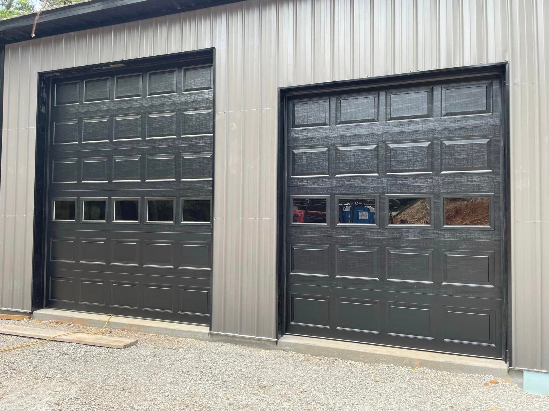 There are two garage doors on the side of a building.