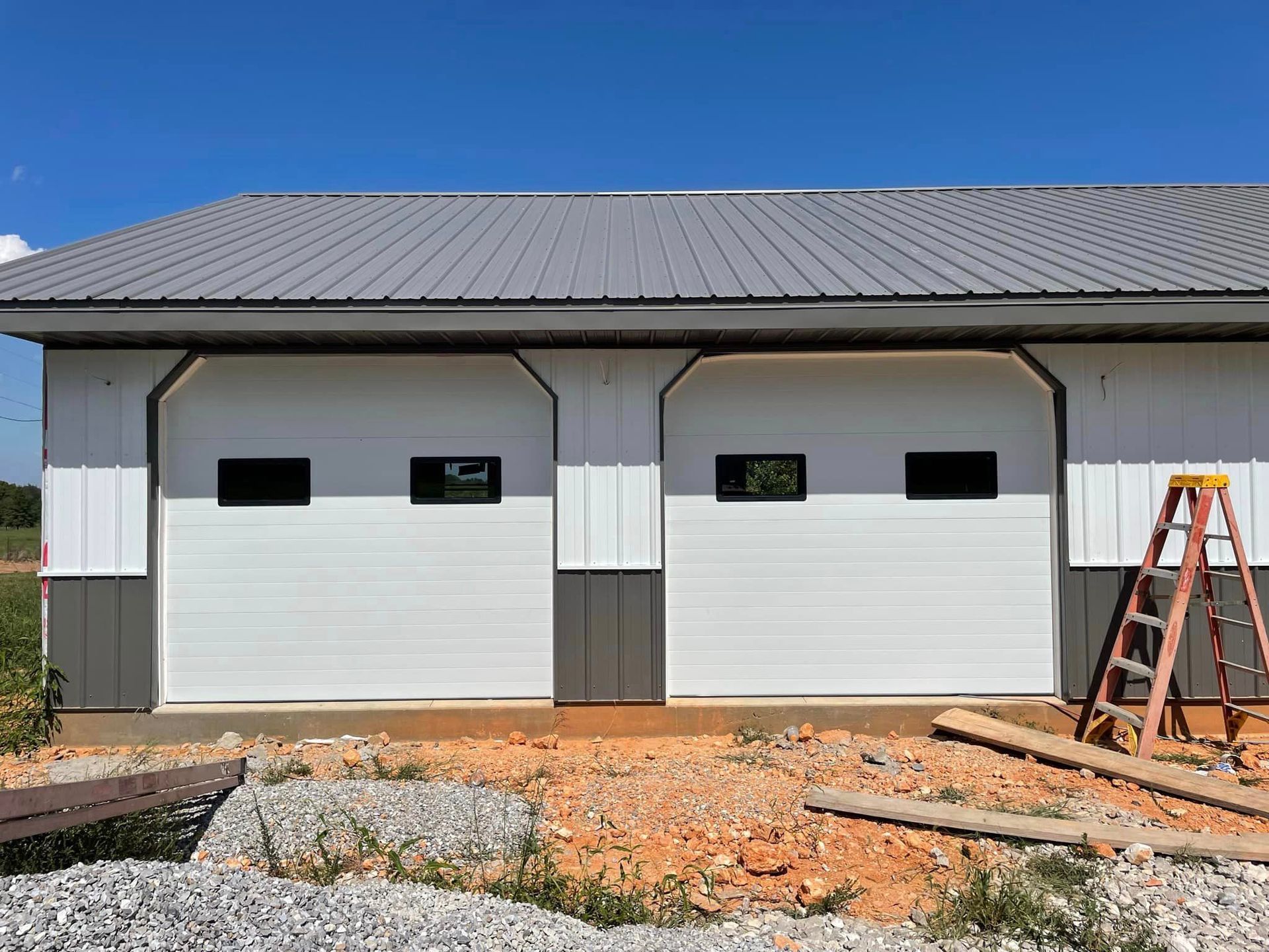 A garage with two garage doors and a ladder in front of it.