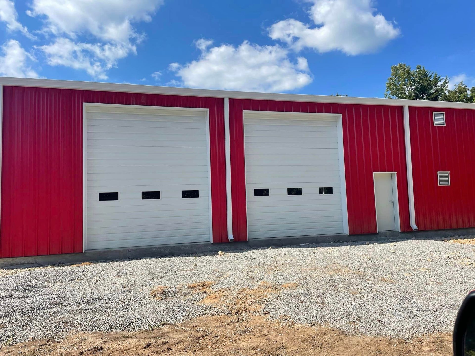 A red building with white garage doors and a door