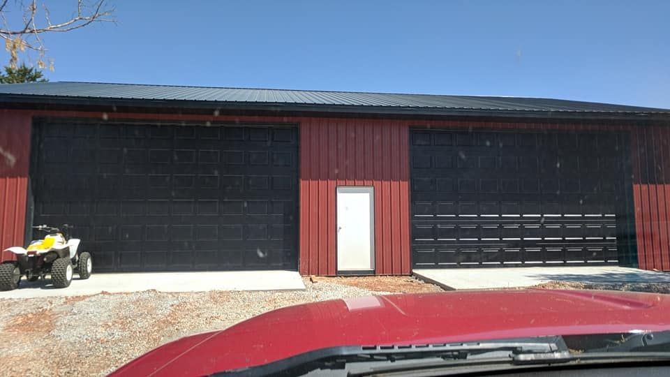 A red truck is parked in front of a garage with a yellow atv parked in front of it.