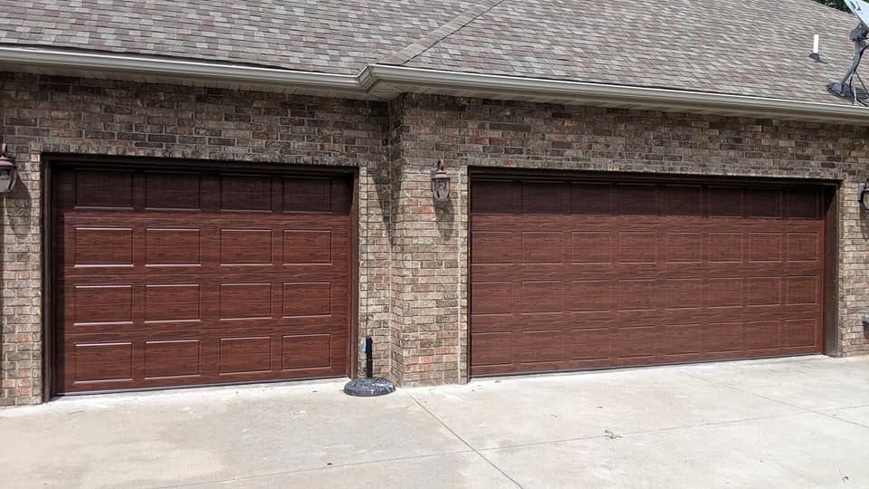 There are two garage doors on the side of a brick building.