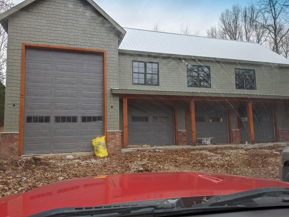 A red car is parked in front of a house under construction