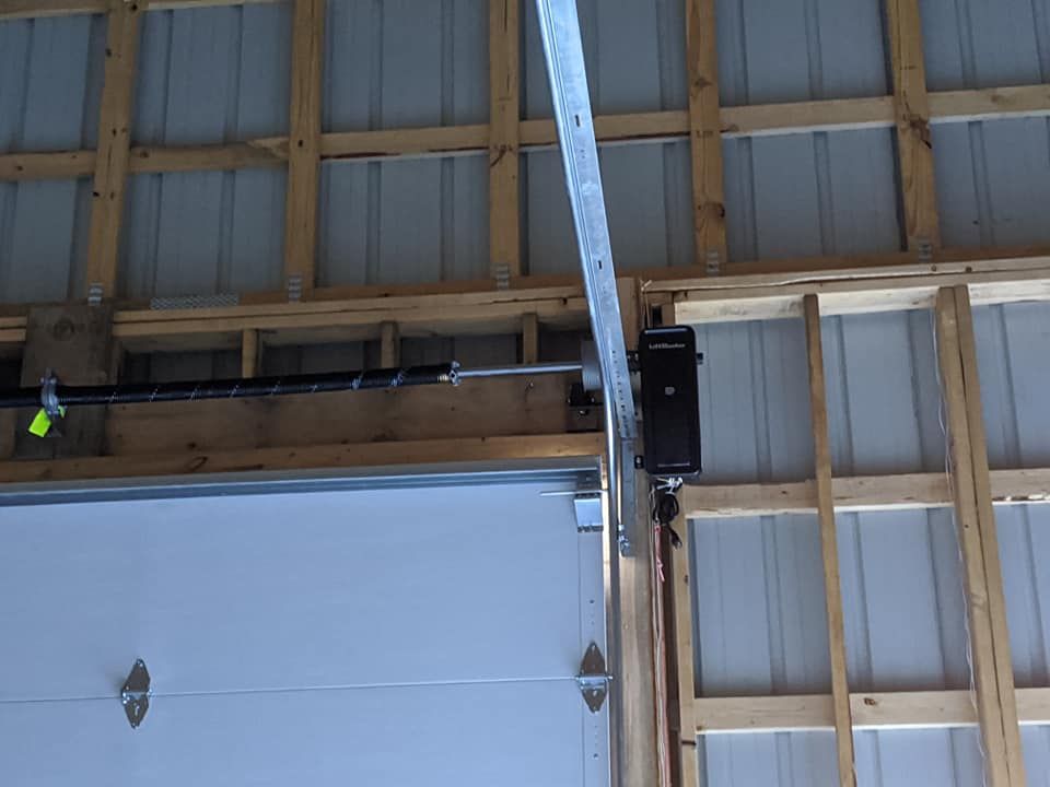 A garage door opener is hanging from the ceiling of a building.