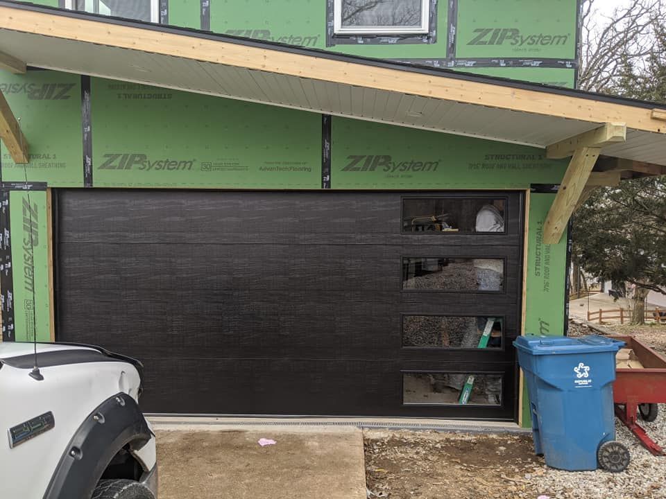 A truck is parked in front of a garage door under construction.