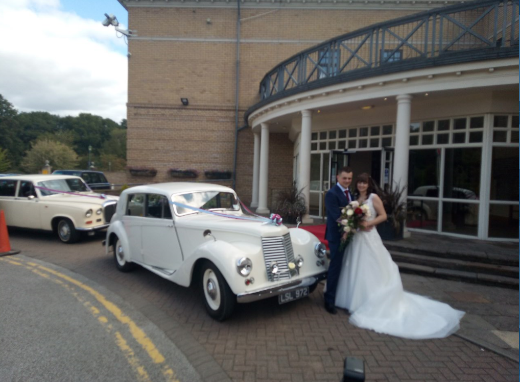 Groom and bride with with vintage wedding car