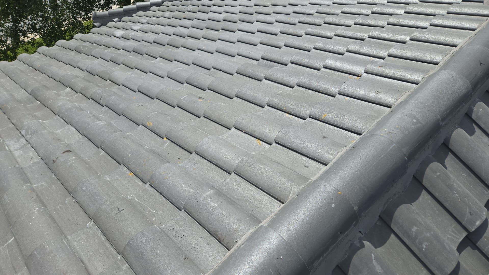 Close-up view of a gray tiled roof with a curved edge detail.