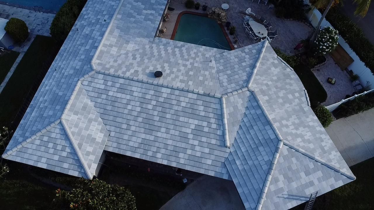 Aerial view of a house with a gray roof and a pool in the backyard.