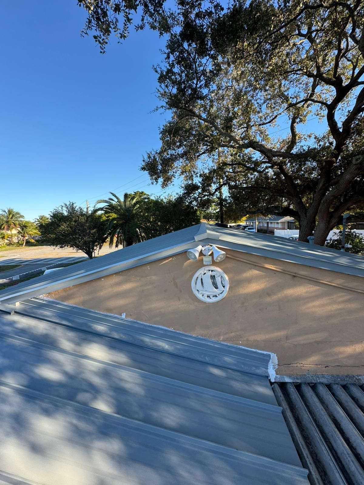 View from a roof shows a beige wall with white circular decoration and security lights. 