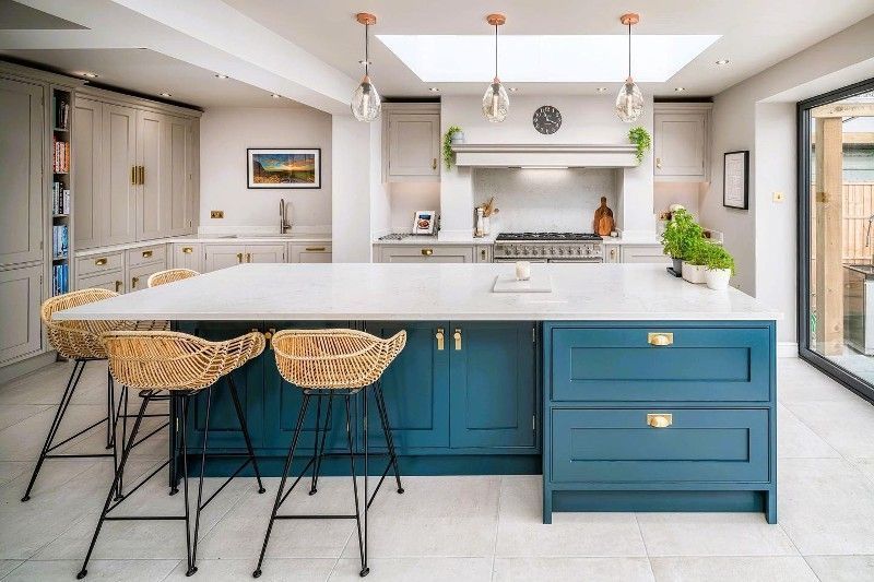 A kitchen with blue cabinets , white counter tops , and wicker stools.