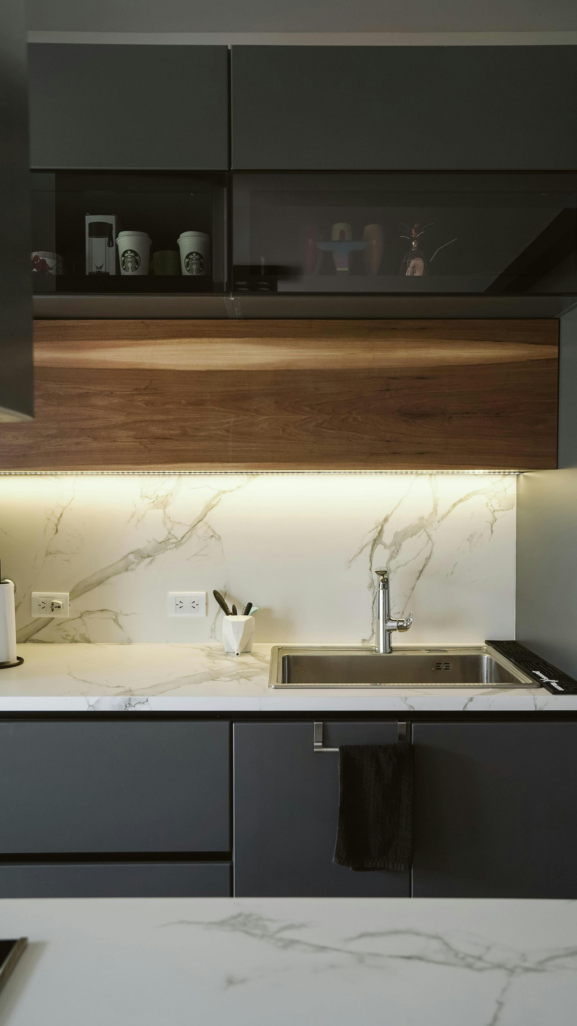 A kitchen with a sink , cabinets , and a marble counter top.