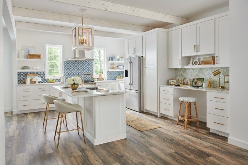 A kitchen with white cabinets , stainless steel appliances , hardwood floors and a large island.