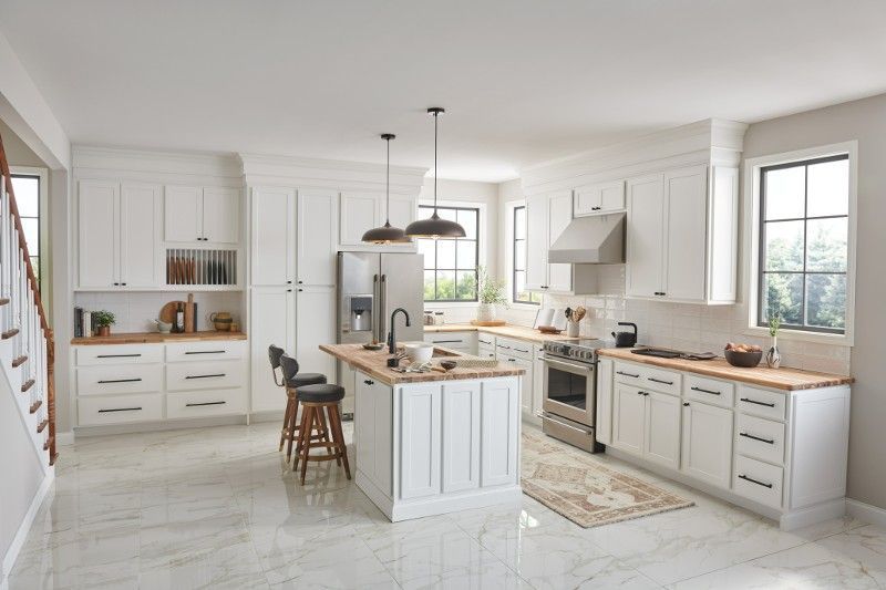 A kitchen with white cabinets , stainless steel appliances , and a large island.