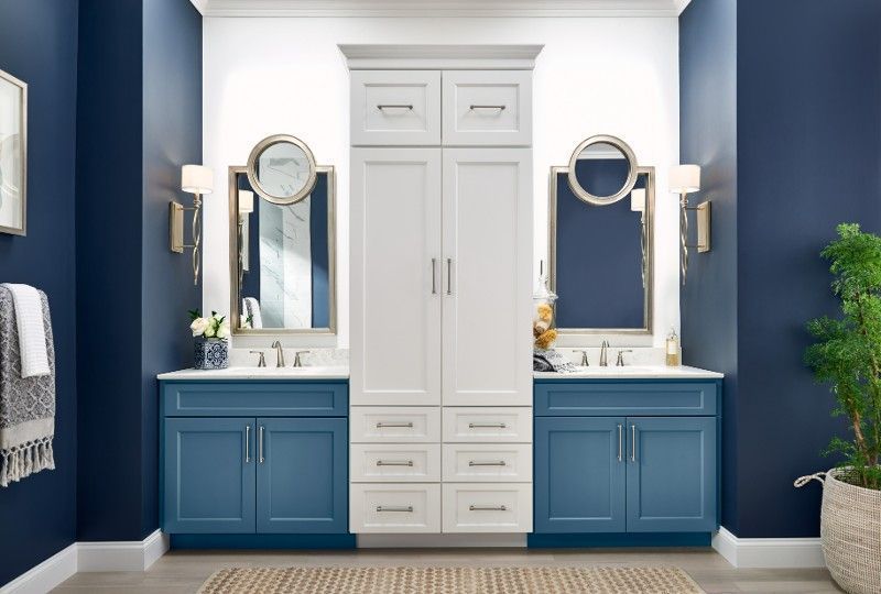 A bathroom with blue cabinets and white cabinets and two sinks.