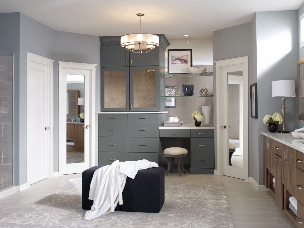 A bathroom with gray cabinets and a black ottoman