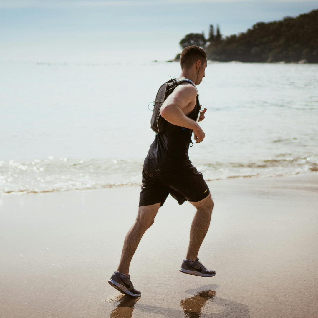 physically fit man running on the beach 