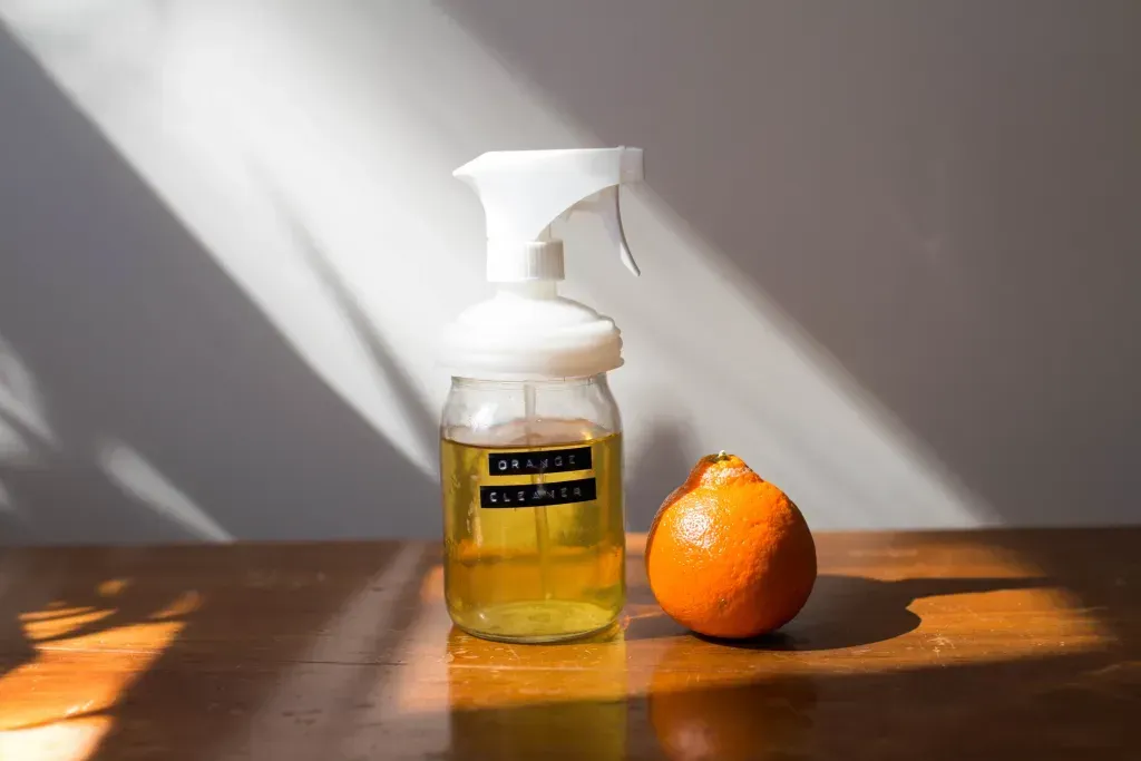 natural orange cleaner in a mason jar spray bottle next to an orange