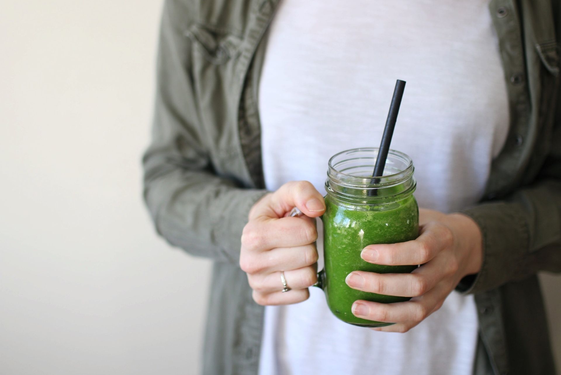 Rebecca holding green smoothie in a glass cup with a straw