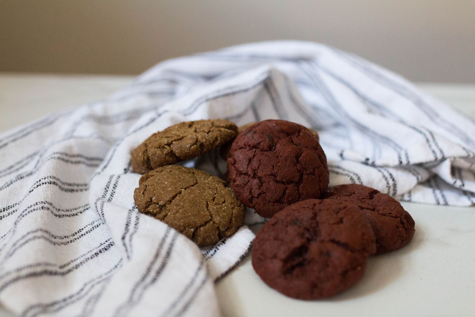 An Assortment of Red Velvet Cookies on a table with a gray stripped towel behind them