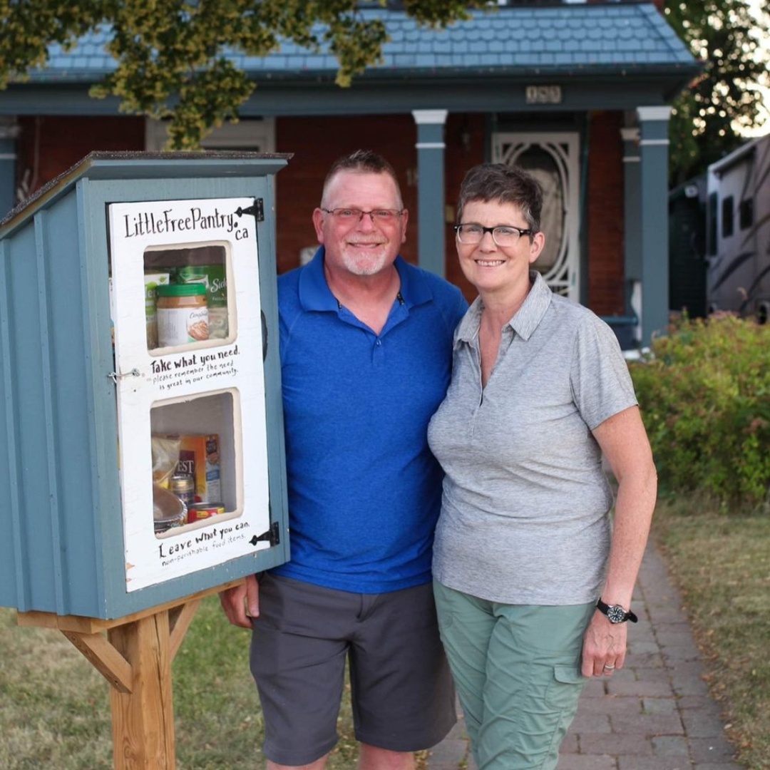 A man and a woman stuff food supplies into a pantry
