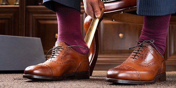 man putting leather shoes on