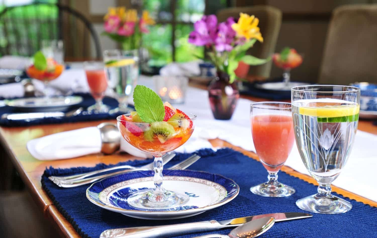 A table with plates , glasses , utensils , and fruit on it.