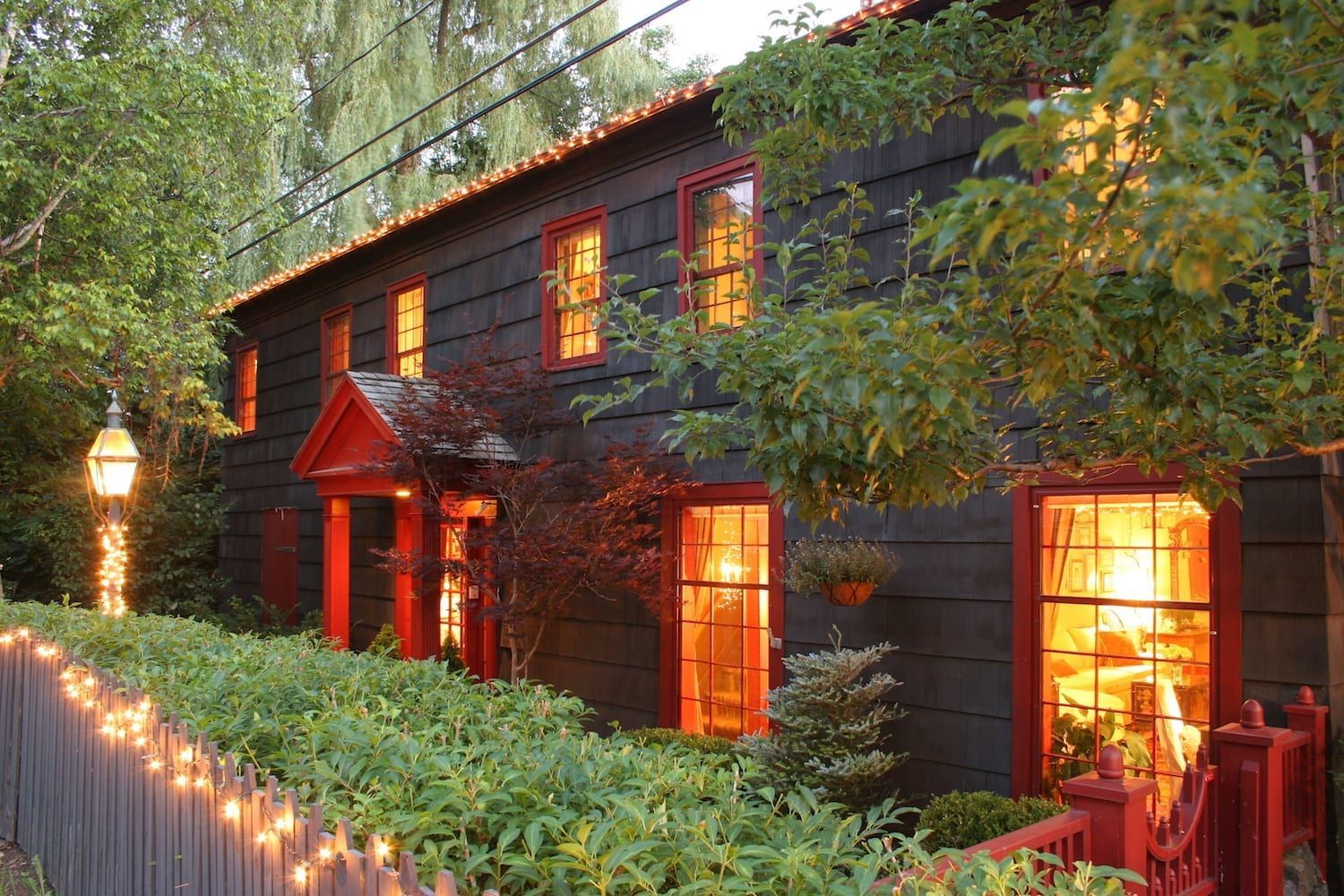 A black house with red trim is lit up at night