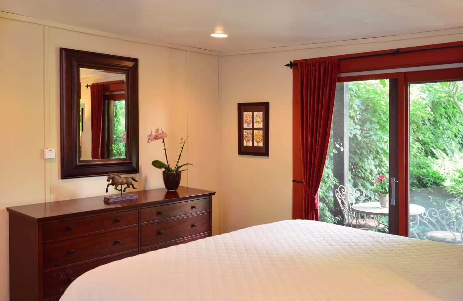 A bedroom with a bed , dresser , mirror and sliding glass doors.