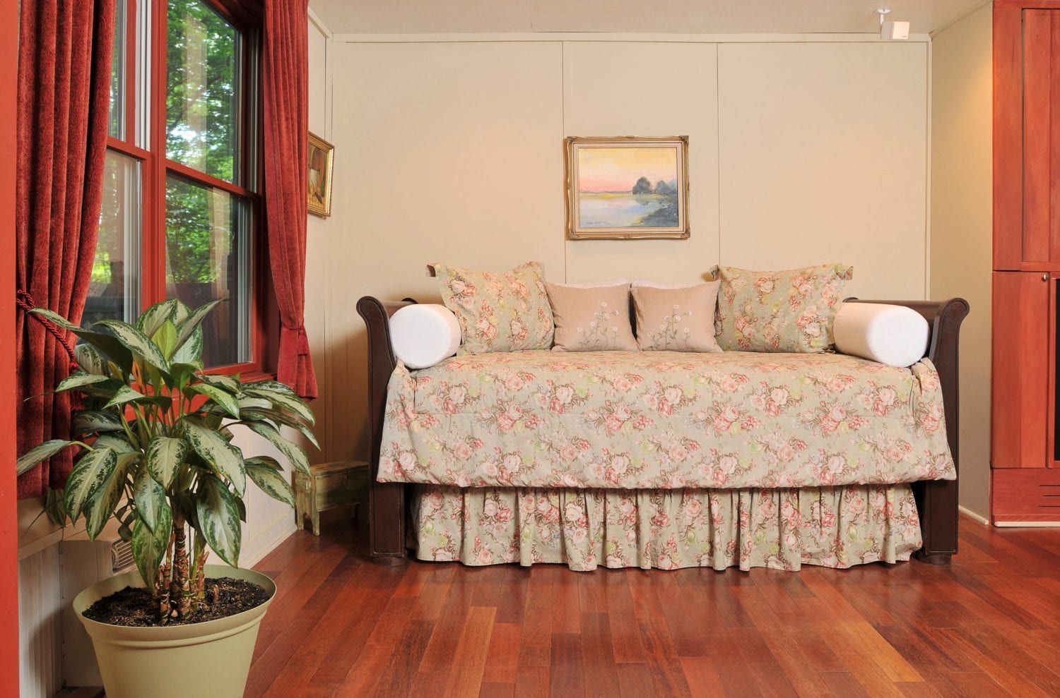 A living room with a day bed and a potted plant