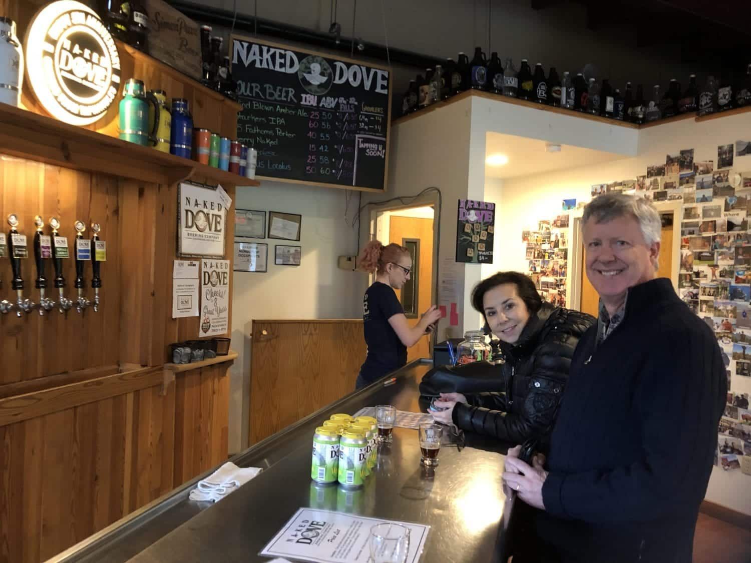 A man and a woman are standing at a bar in a restaurant.