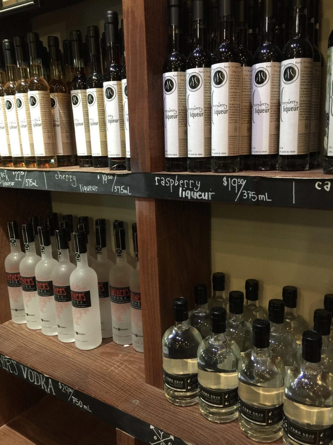 A shelf filled with lots of bottles of alcohol including vodka