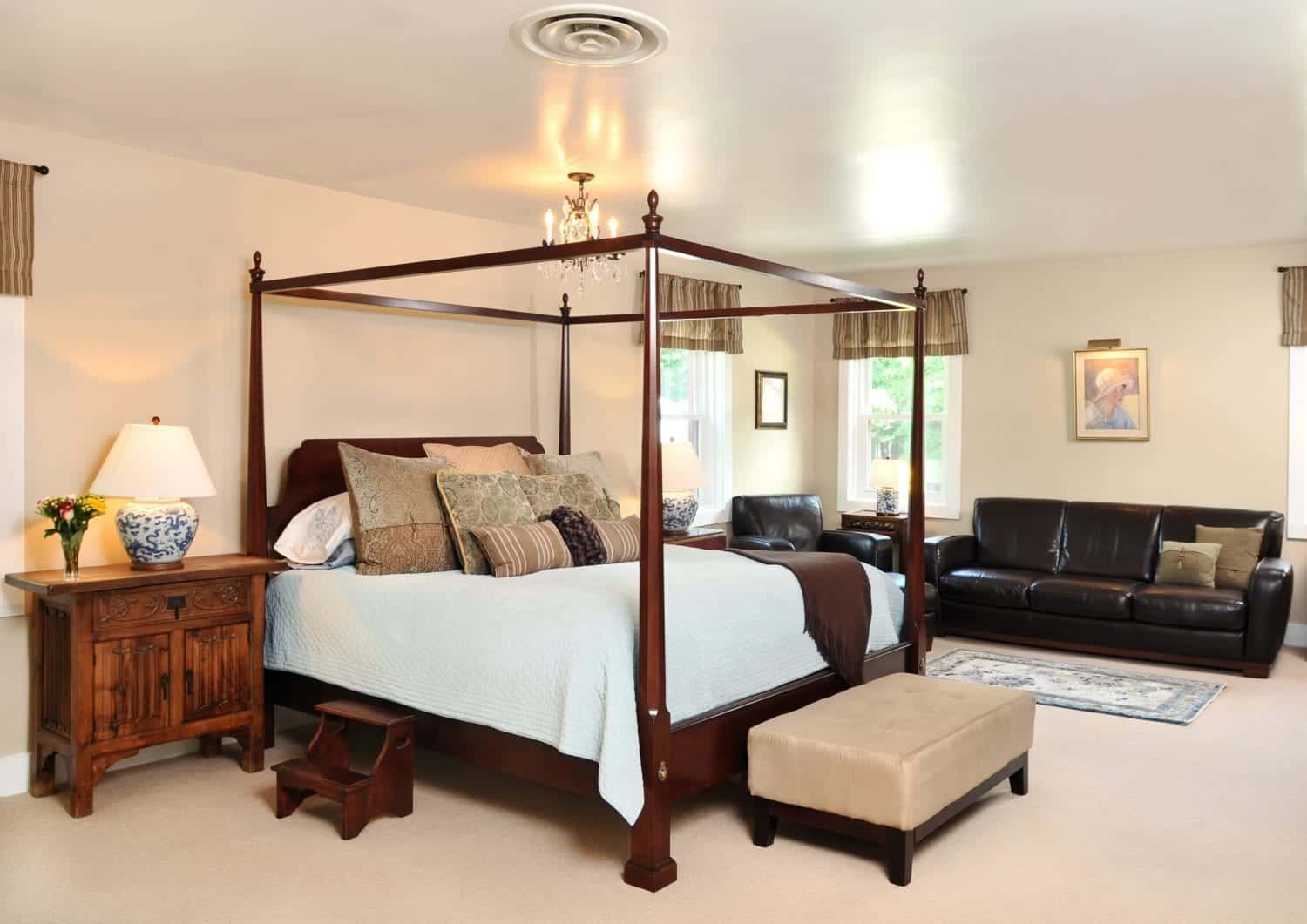 A bedroom with a four poster bed and a couch