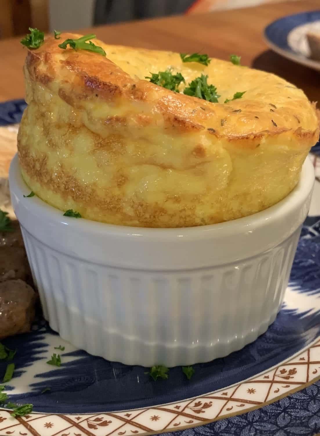 A close up of a souffle in a white bowl on a plate.