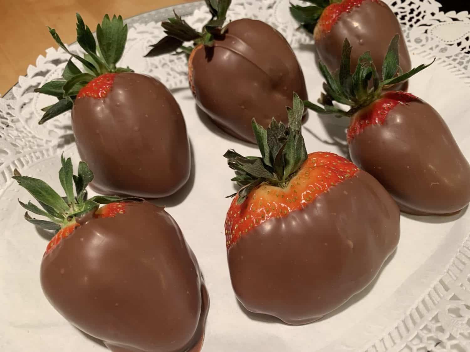 A plate of chocolate covered strawberries on a napkin