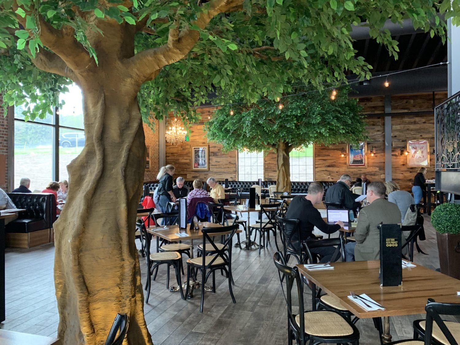 A restaurant filled with people sitting at tables under trees.
