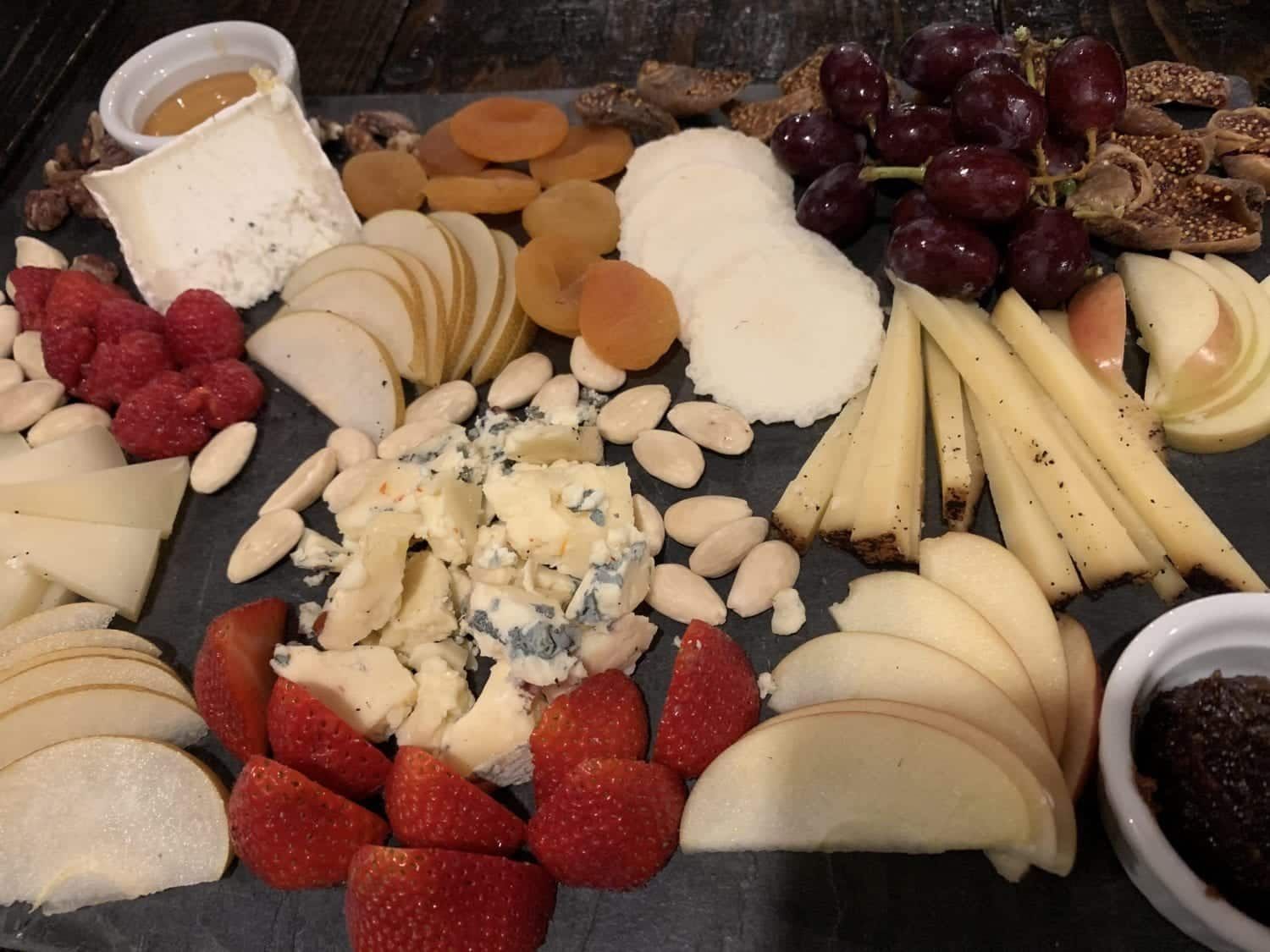 A variety of fruits and cheeses on a cutting board