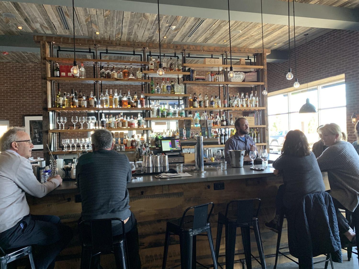 A group of people are sitting at a bar in a restaurant.