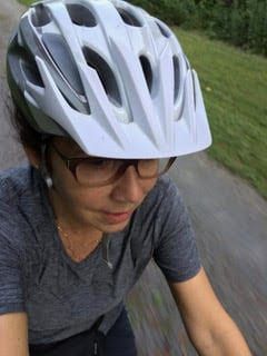 A woman wearing a helmet and glasses is riding a bike down a road.