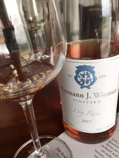 A bottle of hermann j. wiener vineyard dry red wine next to a glass of wine.