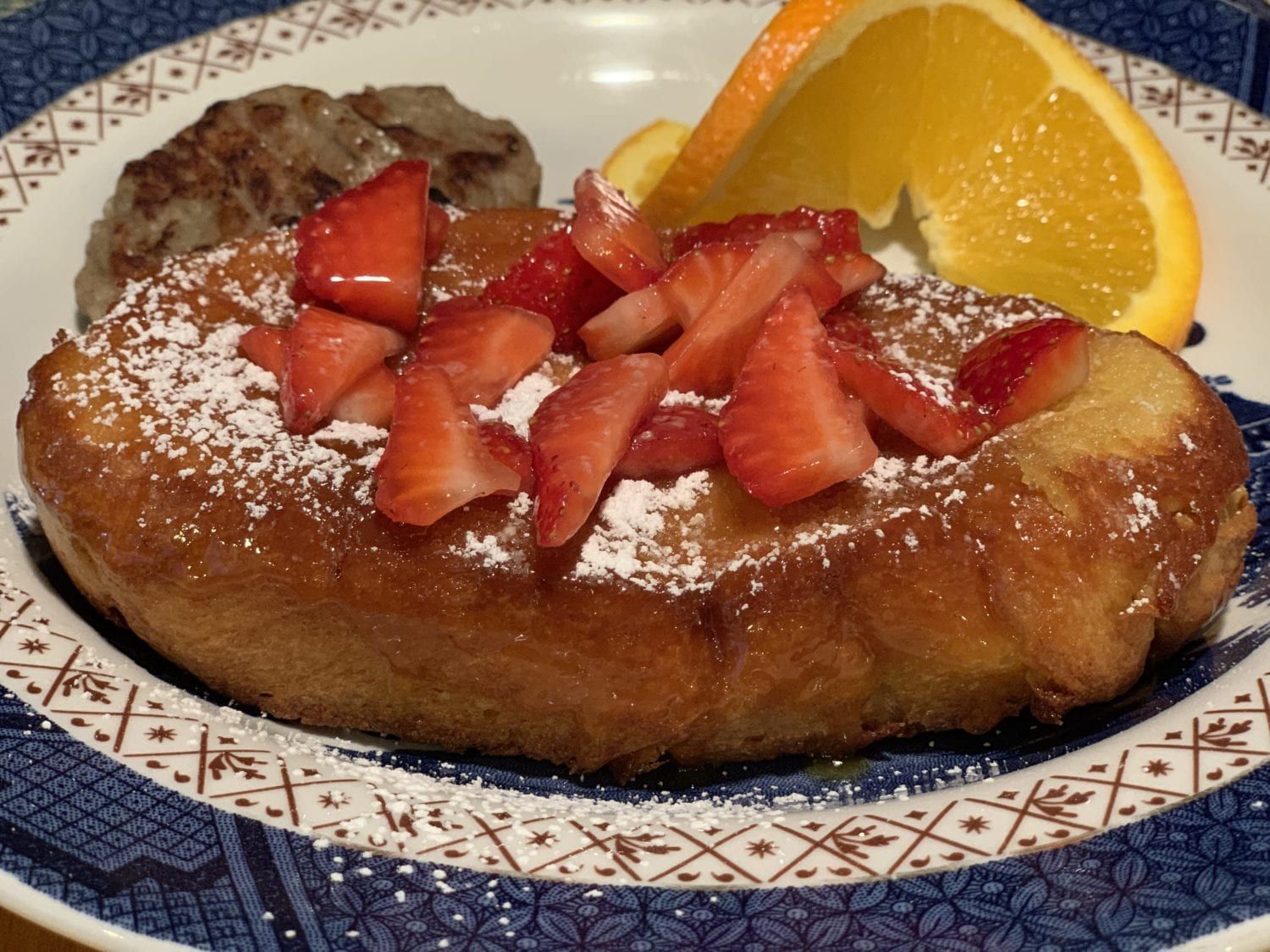 French toast with strawberries and powdered sugar on a plate