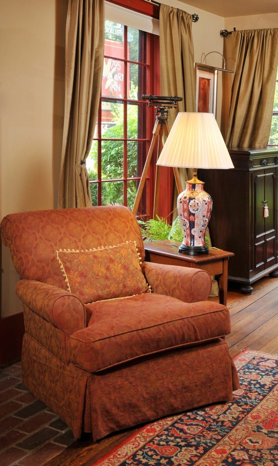 A living room with a chair a lamp and a window