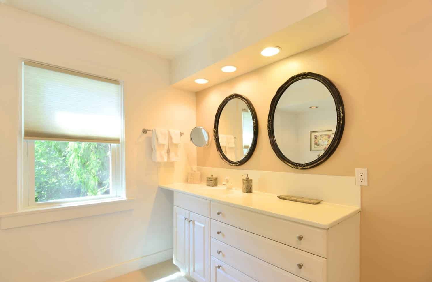 A bathroom with two mirrors on the wall and a window.