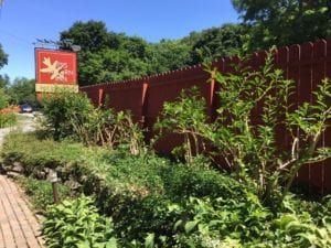 A red fence with a sign on it is surrounded by trees and bushes.