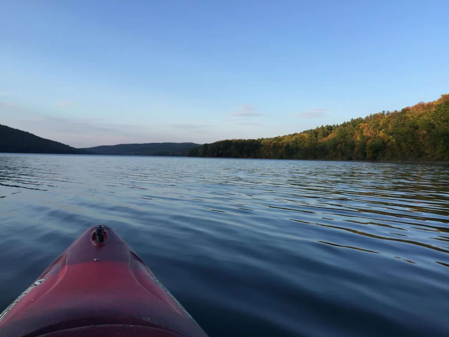 A red kayak is floating on a lake with mountains in the background