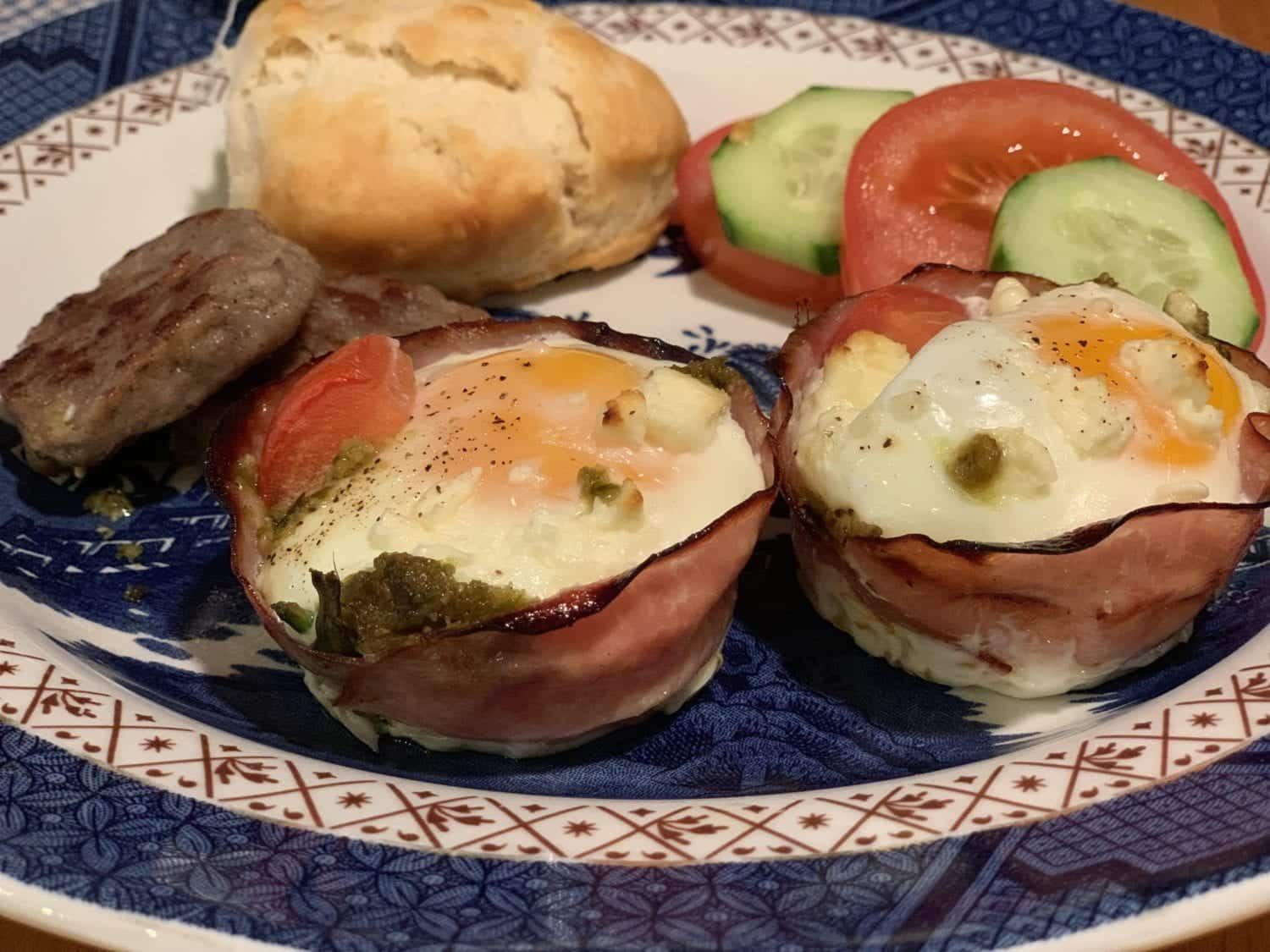 A plate of food with ham eggs tomatoes and cucumbers