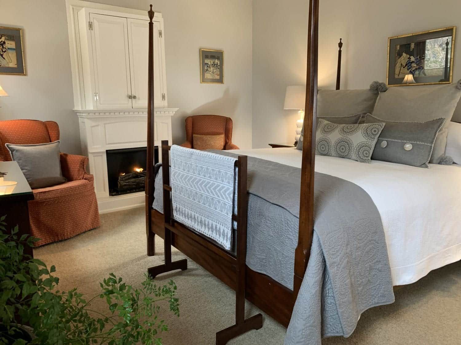 A bedroom with a four poster bed , chair and fireplace.