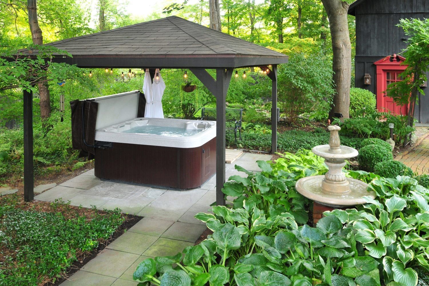 A hot tub is under a gazebo in a garden