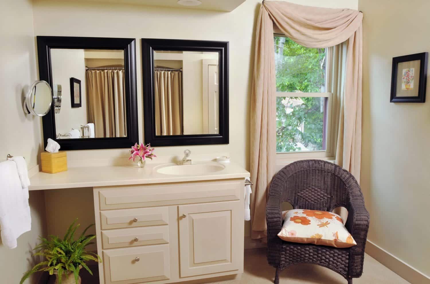 A bathroom with a chair a sink and two mirrors