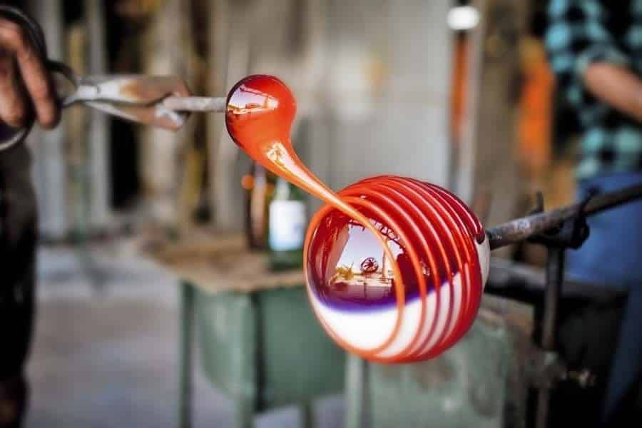 A person is blowing a glass ball with a pair of scissors.